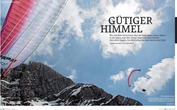 Ein Gleitschirmflieger fliegt vor einer Bergkulisse mit schneebedeckten Gipfeln.