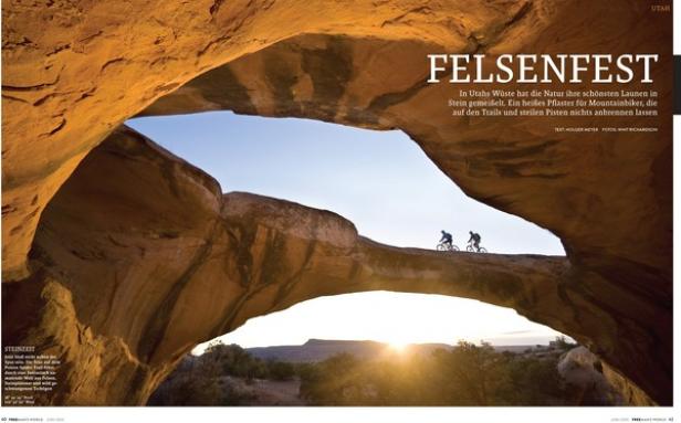 Zwei Mountainbiker fahren auf einem Felsbogen in Utah bei Sonnenuntergang.