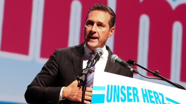 Ein Mann in Anzug spricht am Rednerpult mit der Aufschrift „Unser Herz“.