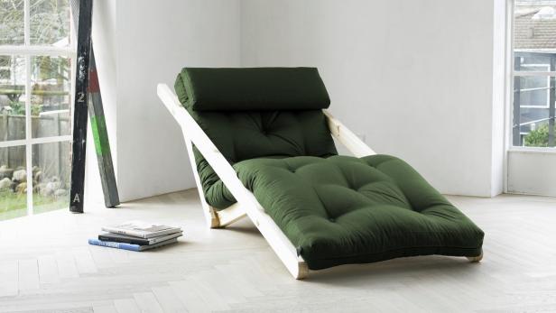 Ein grüner Futon-Sessel mit Holzrahmen steht in einem hellen Raum.