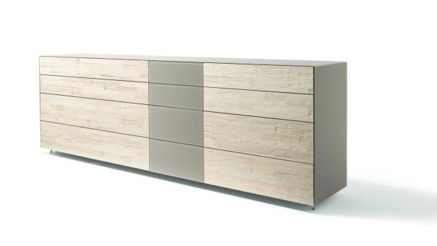 Eine Kommode mit Holzstruktur und grauen Schubladenfronten steht vor einem weißen Hintergrund.