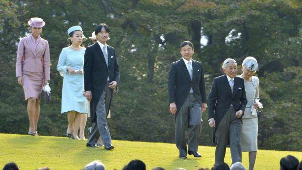 Mitglieder der japanischen Kaiserfamilie gehen über einen grünen Hügel.