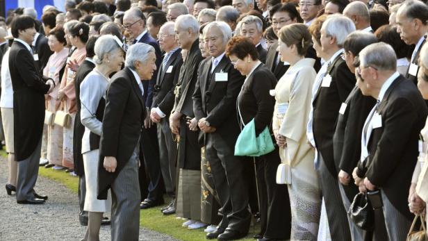 Eine formelle Versammlung von Menschen in Anzügen und traditioneller japanischer Kleidung.