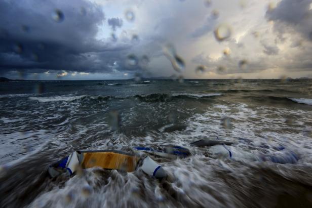 Ein zerstörtes Boot liegt im stürmischen Meer unter einem bewölkten Himmel.