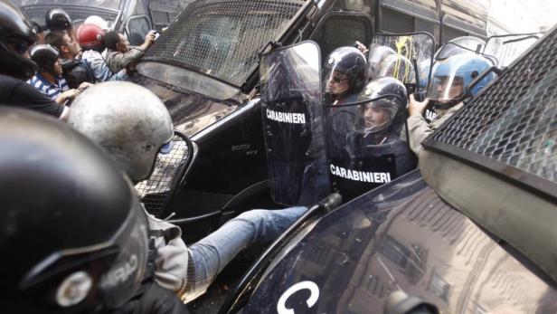 Polizisten der Carabinieri stehen in Schutzausrüstung vor einem Mannschaftswagen.