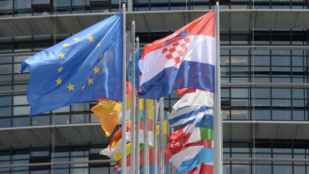 Die Europaflagge und die kroatische Flagge wehen vor einem modernen Gebäude.