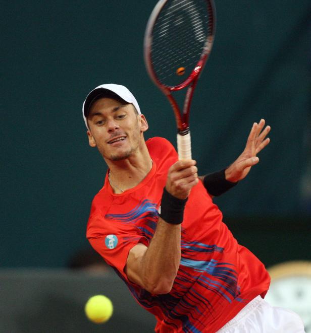 Ein Tennisspieler schlägt einen Ball mit seinem Schläger.