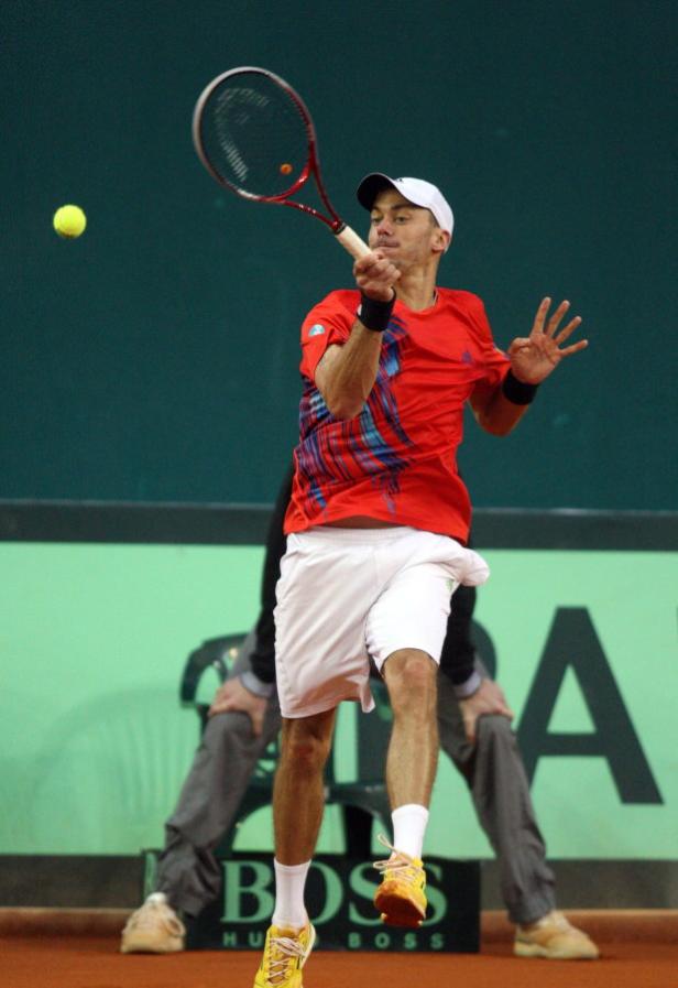 Ein Tennisspieler schlägt einen gelben Ball mit seinem Schläger.