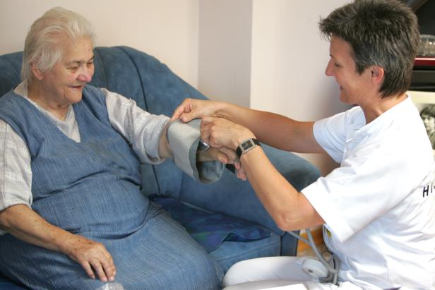 Eine Krankenschwester misst den Blutdruck einer älteren Dame.