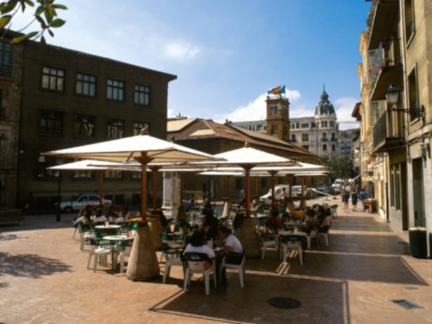 Ein belebter Platz mit Cafés und Menschen in einer europäischen Stadt.