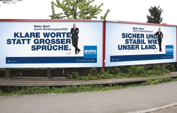 Zwei Werbetafeln der Hypo Oberösterreich mit politischen Slogans und Fotos von Politikern.