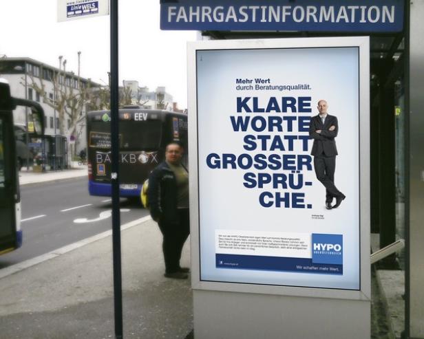 Ein Bushaltestellenschild wirbt mit dem Slogan „Klare Worte statt großer Sprüche“ für Hypo Oberösterreich.