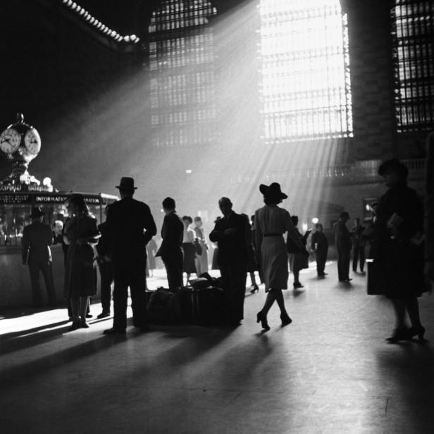 Menschenmenge in einer Bahnhofshalle mit einfallendem Sonnenlicht.
