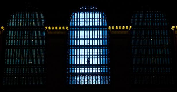 Eine Person geht vor einem großen, beleuchteten Fenster.