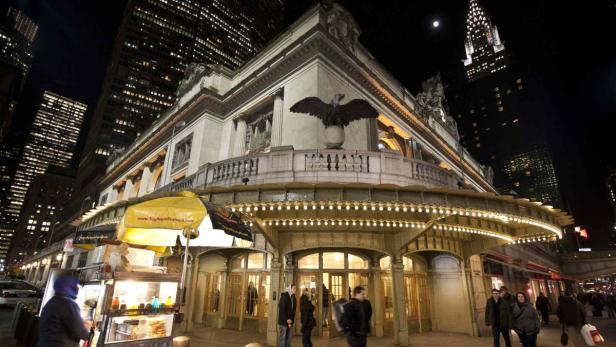 Der Grand Central Terminal in New York bei Nacht, mit dem Chrysler Building im Hintergrund.