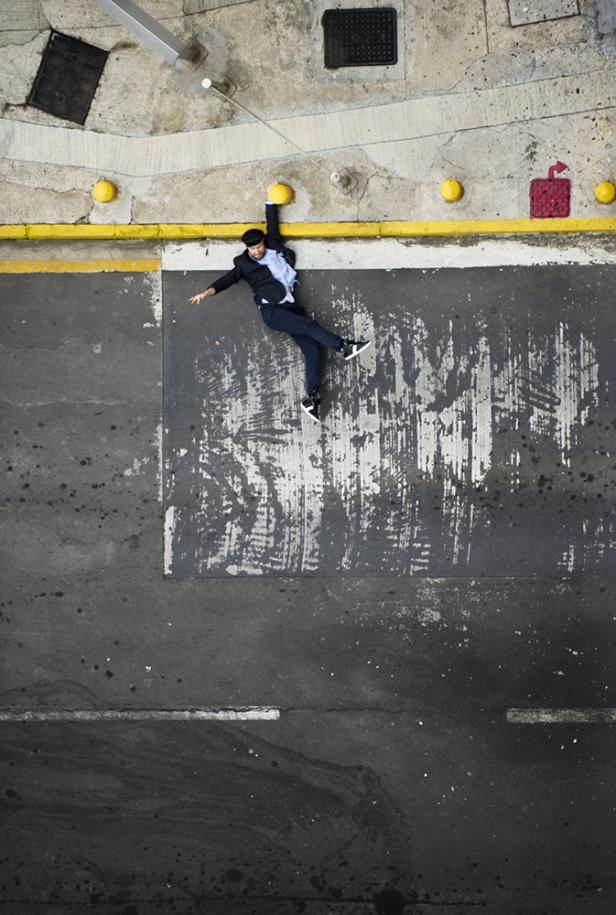 Ein Mann in Anzug und Turnschuhen balanciert auf einer gelben Linie auf einer Betonfläche.