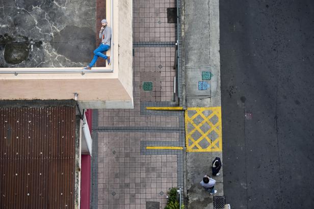 Ein Mann sitzt auf dem Dach eines Gebäudes, von oben fotografiert.