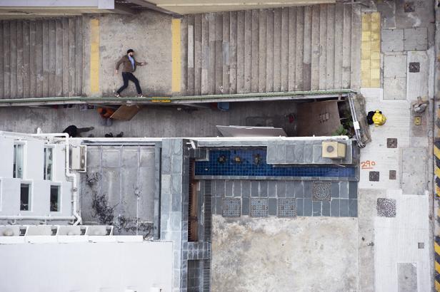 Ein Mann geht auf einem schmalen Sims neben einer Treppe entlang.