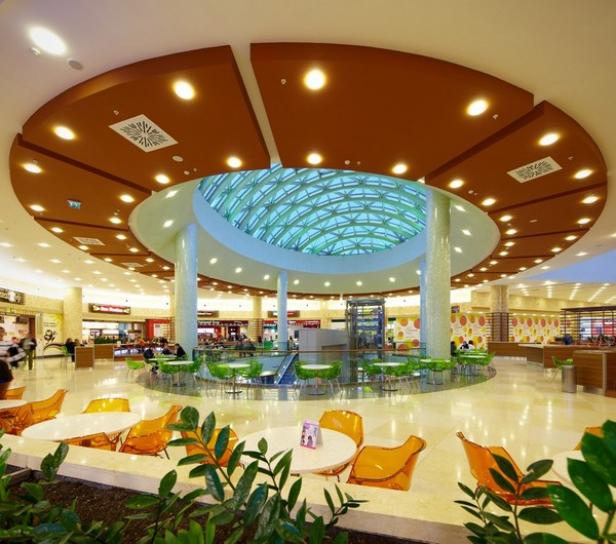 Morgen: Shopping Center werden Warenpräsentations-, Entertainment- und Kommunikationsorte mit kleineren Einzelhandelsflächen, die ausschließlich als Waren-Erlebenis-Punkte fungieren. (c: arthitectural.com) Innenansicht eines Einkaufszentrums mit Oberlicht und Sitzgelegenheiten.