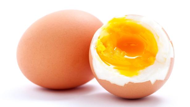 Ein hartgekochtes Ei, angeschnitten, neben einem ganzen Ei.