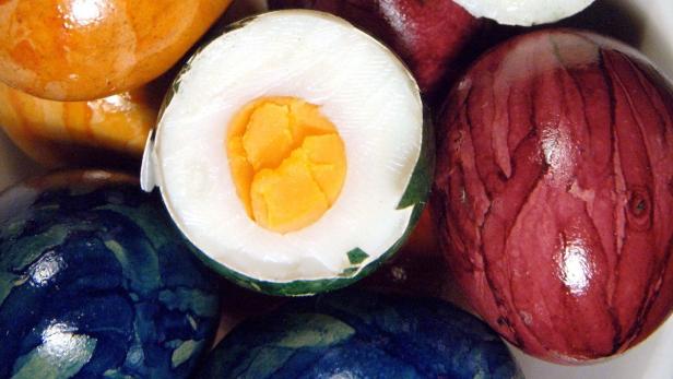 Mehrfarbig bemalte Ostereier, eines davon halbiert.