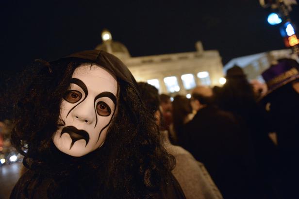 Eine Person mit einer gruseligen Maske und dunkler Kapuze steht im Dunkeln.