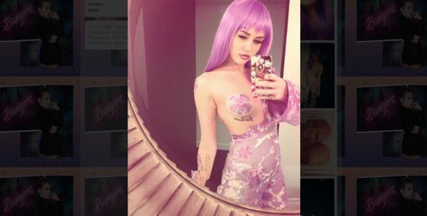 Miley Cyrus macht ein Selfie mit lila Perücke und Herz-förmigem Nippel-Aufkleber.