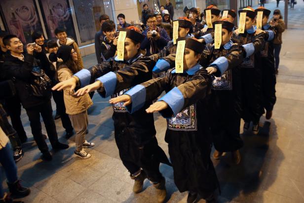 Eine Gruppe von Menschen in traditionellen chinesischen Kostümen tanzt auf der Straße.
