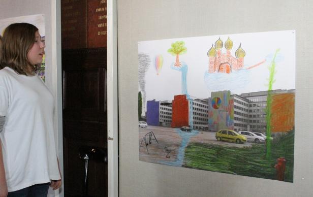 Ein Kind betrachtet ein farbenfrohes, naives Kinderbild mit Gebäuden und Fantasieelementen.