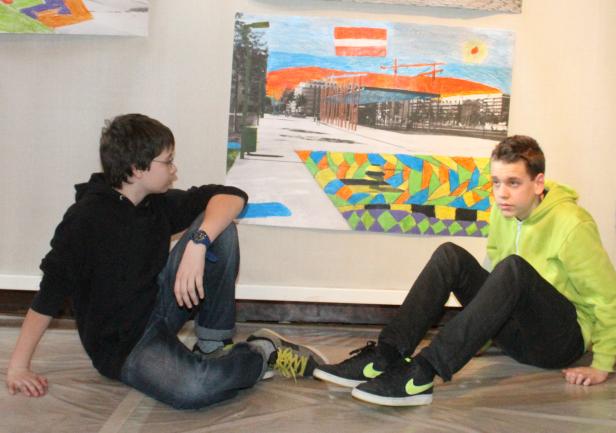 Zwei Jungen sitzen vor einem großen, farbenfrohen Bild mit der österreichischen Flagge.