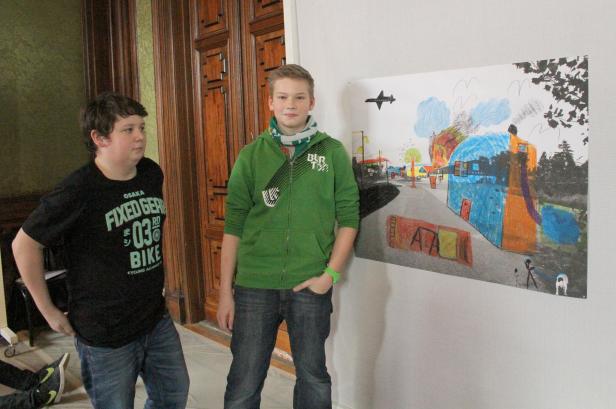 Zwei Jungen stehen vor einer bunten Kinderzeichnung an der Wand.