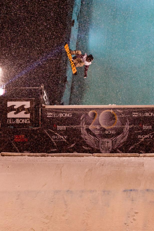 Ein Snowboarder springt während eines nächtlichen Wettbewerbs über eine Rampe.