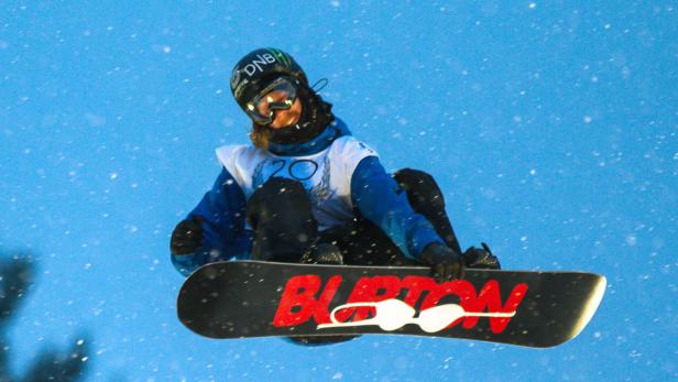 Ein Snowboarder springt in der Luft vor einem blauen Himmel.