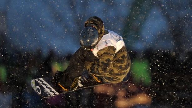 Ein Snowboarder springt in der Luft während es schneit.