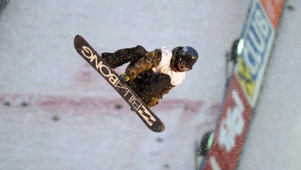 Ein Snowboarder springt in der Luft mit einem Billabong-Board.