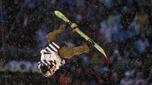 Ein Skifahrer macht einen Trick in der Luft vor einer Zuschauermenge.