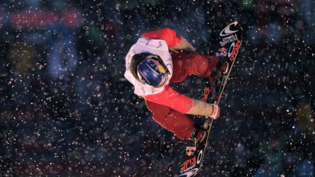 Ein Snowboarder springt in der Luft während es schneit.