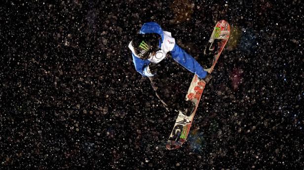 Ein Snowboarder springt in der Luft während es schneit.