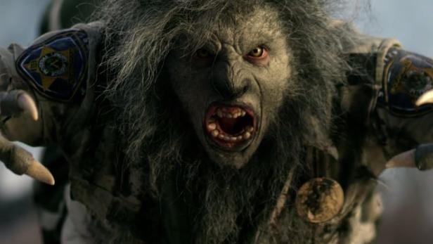 Ein Werwolf in einer Polizeiuniform mit aufgerissenem Maul und gelben Augen.