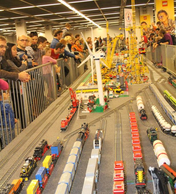Viele Menschen betrachten eine detailreiche Modelleisenbahn aus Lego mit Windrad und Kränen.
