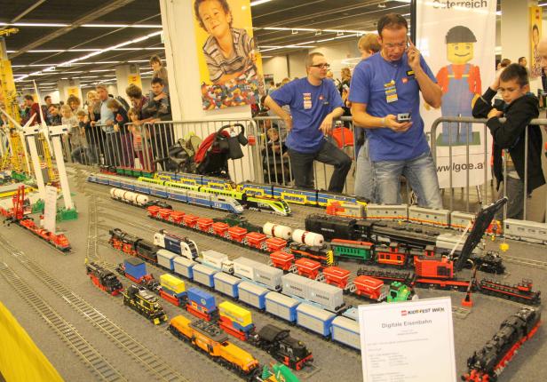 Eine Ausstellung mit verschiedenen Modelleisenbahnen aus Lego, umringt von Zuschauern.