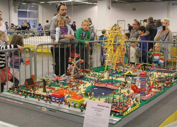 Besucher betrachten einen detailreichen LEGO-Nachbau des Wiener Praters mit Riesenrad und anderen Attraktionen.
