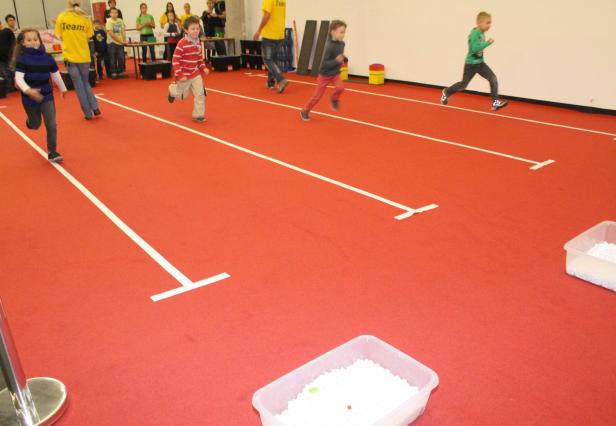 Kinder laufen auf einer roten Bahn um die Wette.