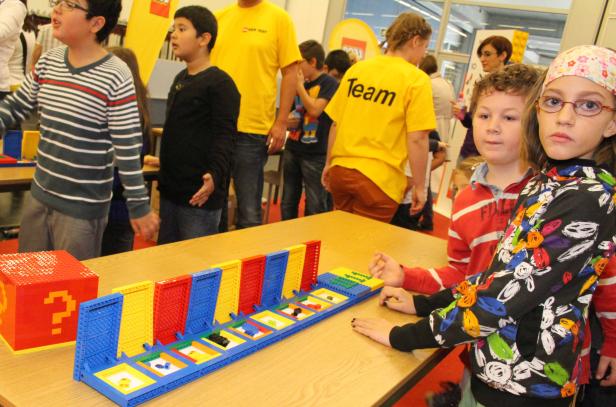 Kinder spielen mit einem Lego-Bausatz an einem Tisch.