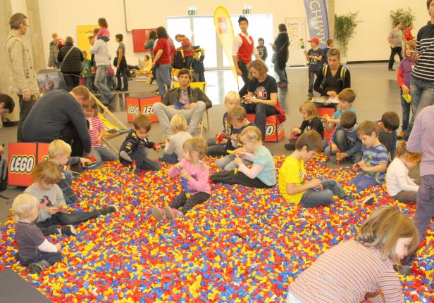 Kinder spielen in einem Becken voller bunter Legosteine.