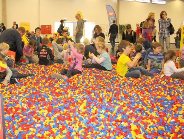 Kinder spielen in einem Becken voller bunter Legosteine.