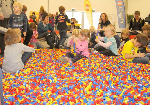 Kinder spielen in einem Becken voller bunter Legosteine.