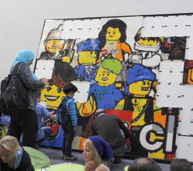 Besucher betrachten ein großes Lego-Mosaik mit Comicfiguren.