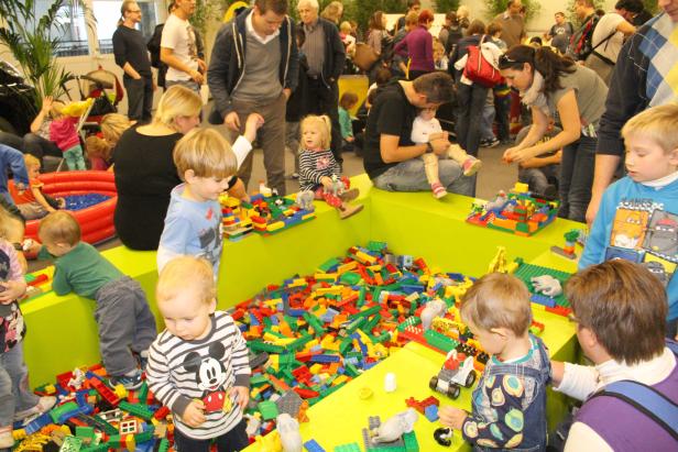 Kinder spielen mit bunten Bauklötzen in einem hellgrünen Becken.