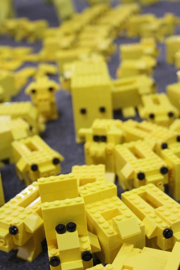 Viele gelbe Lego-Figuren stehen auf einer grauen Oberfläche.